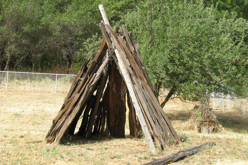 Umacha (house) Built with cedar poles for stability. Wrapped with grape vines to hold it together and covered with cedar bark. Pine needles were laid on the floor for comfort, and a fire pit in the middle for warmth.
